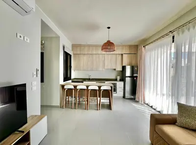a kitchen with wooden cabinets and bar stools at Makadi Heights Luxury 1-BR App with Garden & Lagoon View in Hurghada