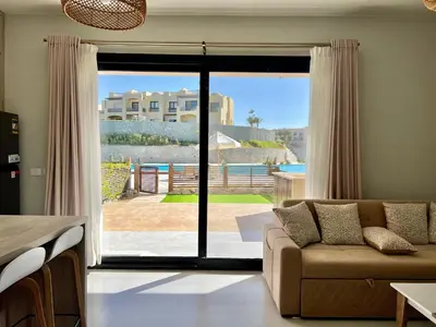 a living room with a couch and a sliding glass door at Makadi Heights Luxury 1-BR App with Garden & Lagoon View in Hurghada