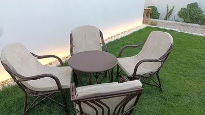 three chairs and a table on a lawn at Relaxing Lodge in Luxor in ‘Ezbet Abu Ḥabashi