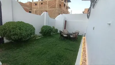 a patio with a table and chairs in a yard at Relaxing Lodge in Luxor in ‘Ezbet Abu Ḥabashi