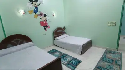 a bedroom with two beds and a wall with mickey mouse decals at Relaxing Lodge in Luxor in ‘Ezbet Abu Ḥabashi
