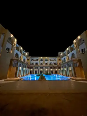 a large building with a large swimming pool at night at EDElma in Hurghada