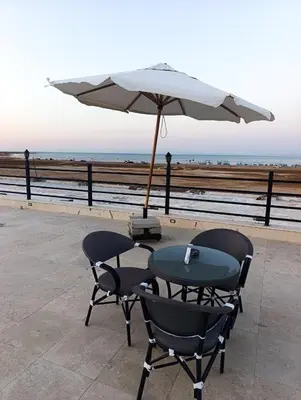 a table and chairs with an umbrella next to the ocean at منتجع اوسيس مارينا in Hurghada