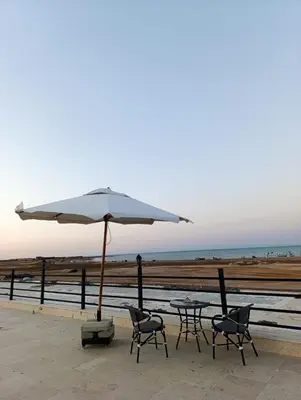 a table and chairs with an umbrella next to the beach at منتجع اوسيس مارينا in Hurghada
