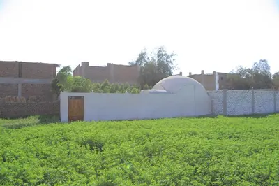 a white building in a field next to a fence at House of Tranquility in Al Aqālitah