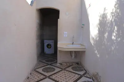 a bathroom with a sink and a washing machine at House of Tranquility in Al Aqālitah