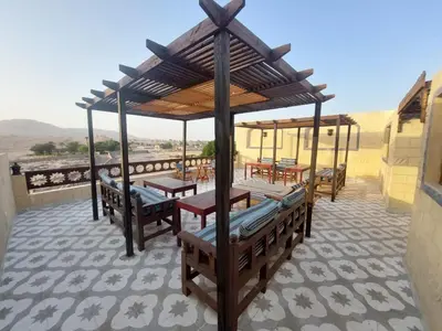 a patio with benches and tables on a roof at Carter Guesthouse Luxor 5 in ‘Ezbet Abu Ḥabashi