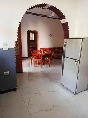 a dining room with a table and a refrigerator at Villa Nicole in Luxor