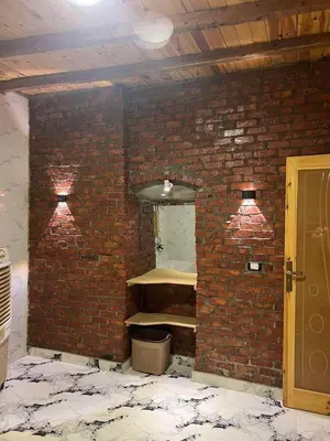 a room with a brick wall with a shelf in it at Djorff studio in Al Aqālitah