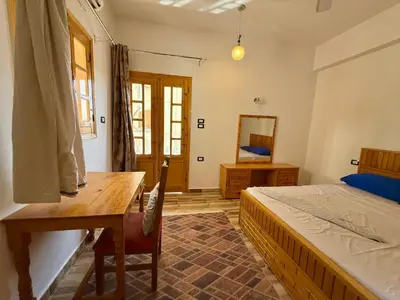 a bedroom with a bed and a wooden table at El Fayrouz Guesthouse Luxor in Luxor