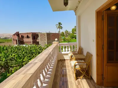 a balcony with chairs and a view of a building at El Fayrouz Guesthouse Luxor in Luxor