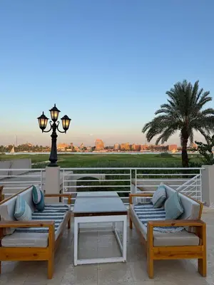 a patio with chairs and tables and a street light at Royal Nile Villa - Luxury Nile Sky Penthouse 1 in Al Aqālitah