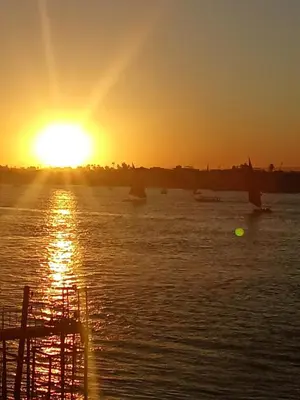 a sunset over a body of water with boats at Elbess For Toursim in Luxor