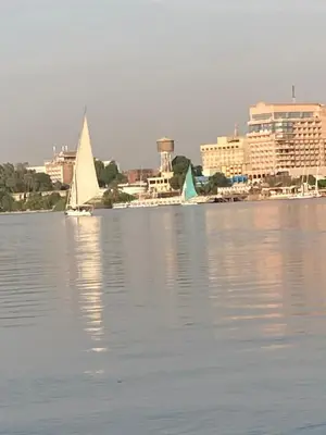 two sailboats on the water with a city in the background at Elbess For Toursim in Luxor
