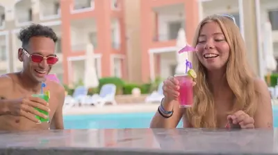 a man and a woman sitting at a table with drinks at Oyster Bay Beach Suites in Marsa Alam