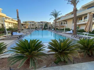 a large swimming pool with palm trees in a resort at Modern Studio in G-Cribs El Gouna in Hurghada