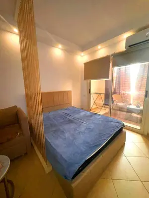 a bedroom with a bed and a couch and a window at Cozy Studio in Hurghada in Hurghada
