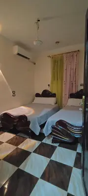 a bedroom with two beds and a checkered floor at Family apartment LUXOR in Jazīrat al ‘Awwāmīyah