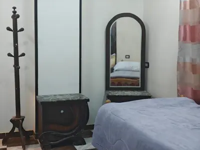 a bedroom with a bed and a mirror at Family apartment LUXOR in Jazīrat al ‘Awwāmīyah