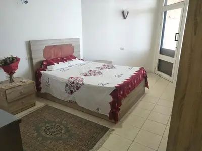 a bedroom with a bed with a red and white blanket at Apartment Sama Beach in Hurghada