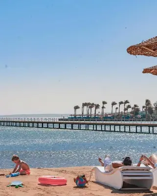 a group of people laying on the beach near the water at Scandic resort in Hurghada