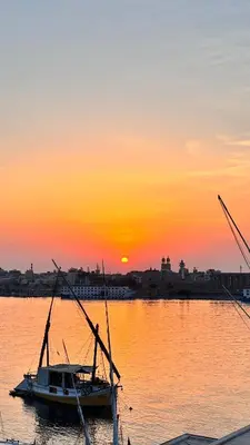 a boat sitting on the water at sunset at Luxor temple view in Luxor