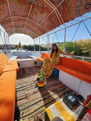 a woman sitting on the back of a boat at Taha nubian boat in Jazīrat Aswān