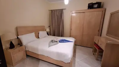 a bedroom with a bed with white sheets and a window at Sahl Hasheesh Aparthotel Beachfront - SAHLHOMES in Hurghada
