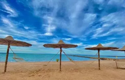 a group of straw umbrellas on a beach at Hurghada Seafront Family Apartment with Pool View in Hurghada