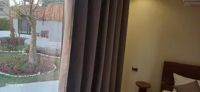 a bedroom with a window with curtains and a garden at Luxury suit with private beach and aquapark in Hurghada