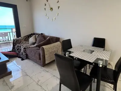 a living room with a couch and a table with chairs at Cozy 1-Bedroom Chalet with Sea View in Hurghada