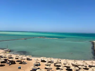 a beach with many umbrellas and the ocean at Cozy 1-Bedroom Chalet with Sea View in Hurghada