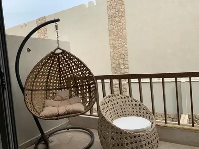 a rattan swing sitting on a balcony with a chair at استوديو أنيق في الجونة in Hurghada