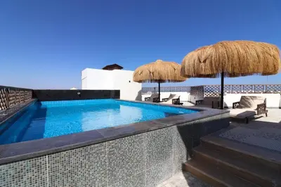 a swimming pool with umbrellas and chairs on a patio at Arabian Suites by Imperial 1 bed Apartment in Hurghada