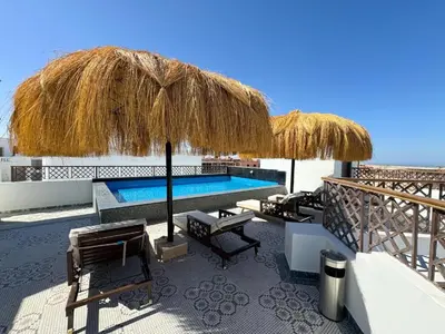 a resort with a swimming pool and straw umbrellas at Arabian Suites by Imperial 1 bed Apartment in Hurghada