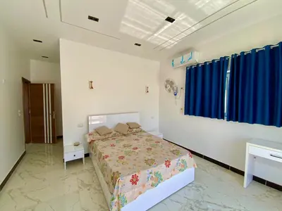 a bedroom with a bed and a blue curtain at Jasmine Villa in Jazīrat al ‘Awwāmīyah