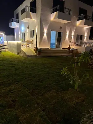 a house with a lawn in front of it at night at Jasmine Villa in Jazīrat al ‘Awwāmīyah