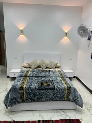 a bedroom with a large bed with two lights on the wall at Jasmine Villa in Jazīrat al ‘Awwāmīyah