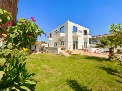 a large white house with a grass yard at Jasmine Villa in Jazīrat al ‘Awwāmīyah