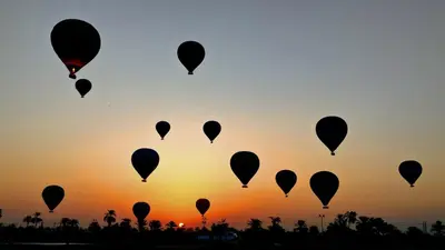 a group of hot air balloons in the sky at sunset at High mountain in Luxor