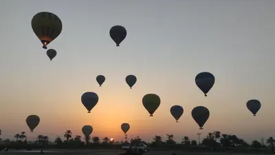 a group of hot air balloons flying in the sky at High mountain in Luxor