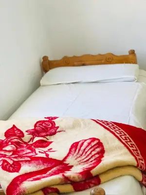 a bed with a red and white blanket on it at ISIS Hostel in Aswan
