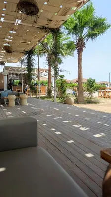 a patio with palm trees and a wooden floor at Selena bay 006 in Hurghada