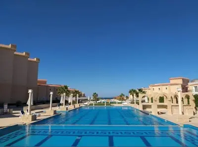 a large swimming pool with palm trees and buildings at Selena bay 006 in Hurghada