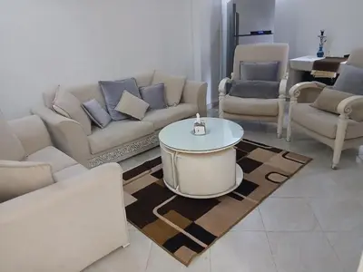 a living room with couches and a table and chairs at Family apartment in front of the sea in Hurghada