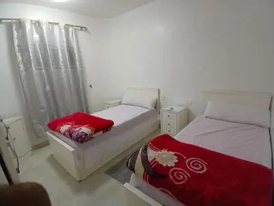 a bedroom with two beds with red and white sheets at Family apartment in front of the sea in Hurghada
