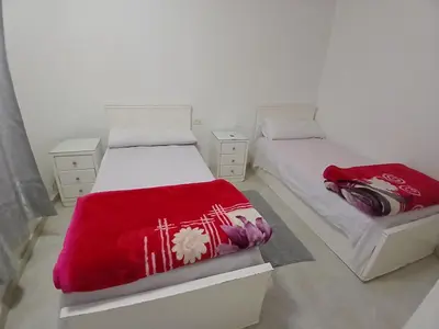 a bedroom with two beds with red blankets at Family apartment in front of the sea in Hurghada