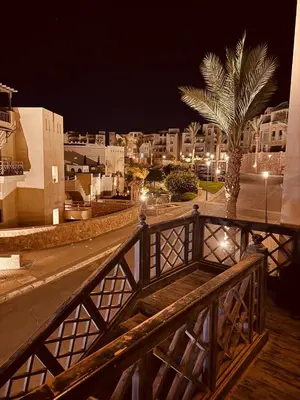 a view of a city at night with a palm tree at Azzura Sahl Hasheesh in Hurghada