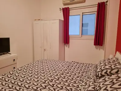 a bedroom with a bed and a window with red curtains at Oasis Resort Soraya - 2 bed apt, recently renovated and fully furnished with pool views in Al Ahyaa Hurghada Egypt in Hurghada