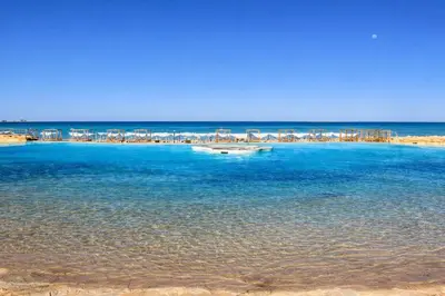 a boat in the water next to a beach at Gravity Apartments Sea View Pool View للأجانب فقط Just For Foreigners in Hurghada